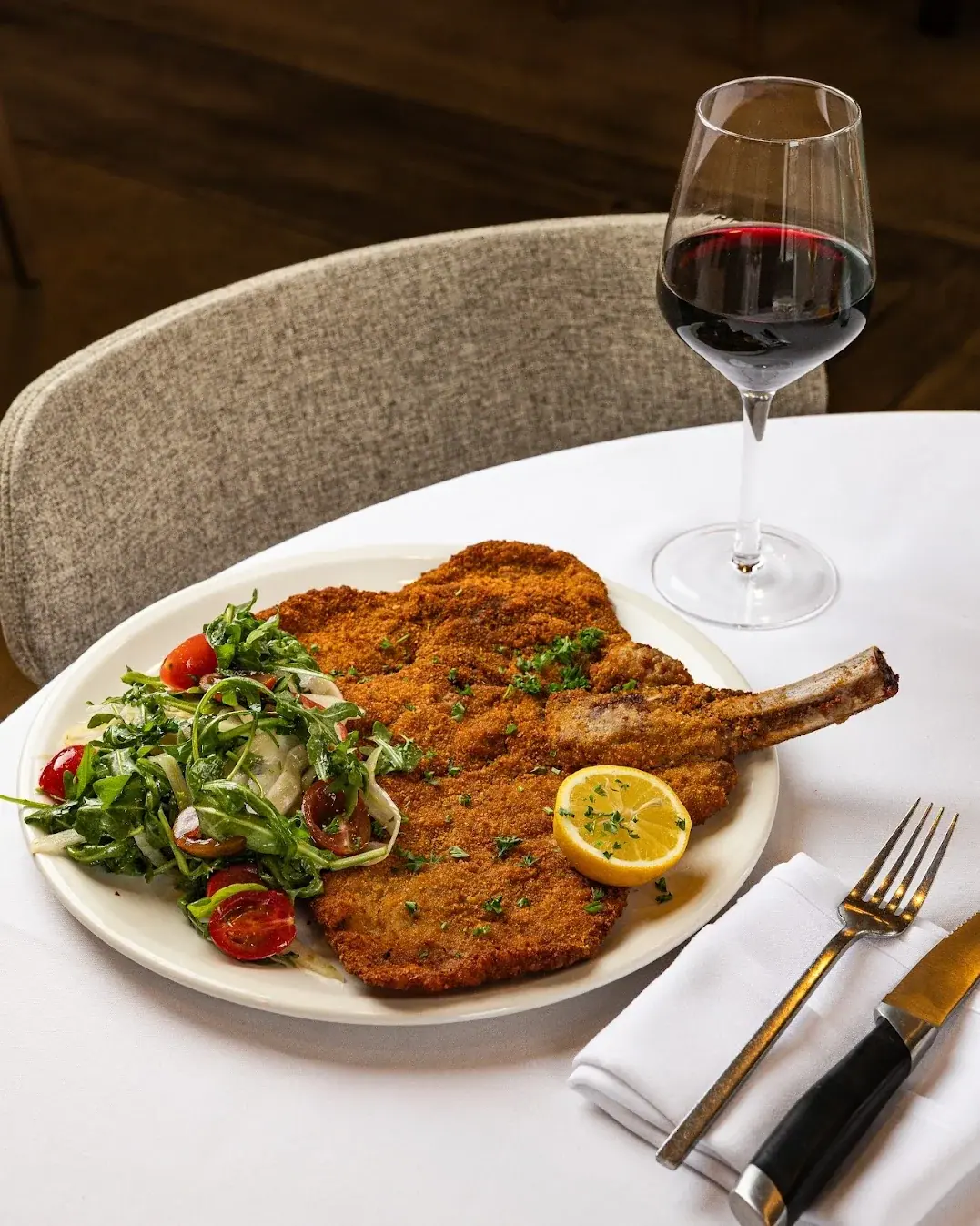 Breaded veal chop with cherry tomatoes and arugula
